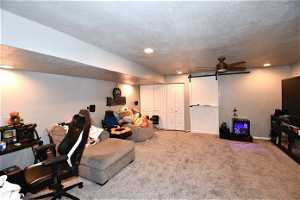 Interior space with a textured ceiling, light carpet, and ceiling fan
