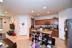 Kitchen with light tile flooring, appliances with stainless steel finishes, and light stone countertops