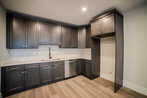 Kitchen featuring dark brown cabinetry, sink, a textured ceiling, dishwasher, and light hardwood / wood-style floors