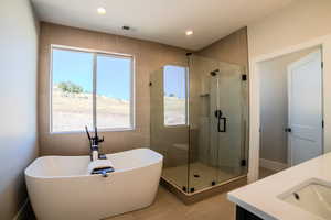 Bathroom featuring shower with separate bathtub, tile patterned flooring, and vanity