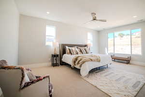 Carpeted bedroom featuring ceiling fan and multiple windows