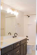 Full bathroom with double sink vanity, tile floors, toilet, and  shower combination