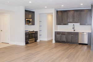 Kitchen with dark brown cabinets, stainless steel appliances, light wood-type flooring, and sink