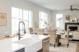 Kitchen featuring ceiling fan, light hardwood / wood-style flooring, a brick fireplace, sink, and dishwasher