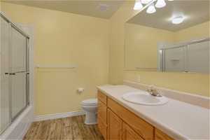 Full bathroom featuring shower / bath combination with glass door, toilet, large vanity, and LVP floors