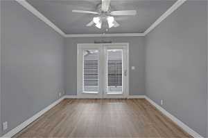 Empty room with a textured ceiling, french doors, ceiling fan, LVP floors, and crown molding