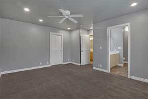 bedroom with ensuite bathroom, ceiling fan, a closet, and dark carpet