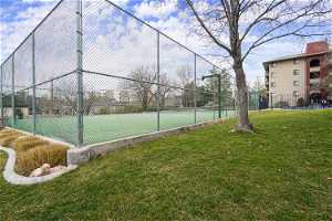 View of sport court featuring a lawn and basketball hoop