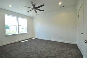 Carpeted primary bedroom with ceiling fan, walk in closet, and grand bathroom.
