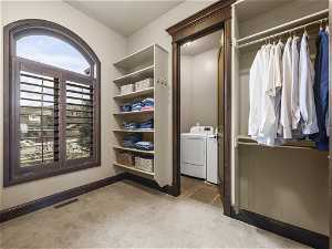 Spacious closet with washing machine and dryer and light colored carpet