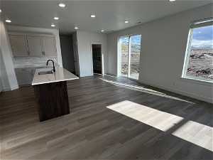 Kitchen with backsplash, gray cabinets, dark wood-type flooring, and an island with sink