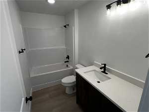 Full bathroom featuring toilet, washtub / shower combination, vanity, and hardwood / wood-style flooring