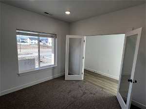 Unfurnished bedroom featuring hardwood / wood-style flooring and french doors