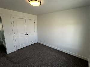 Unfurnished bedroom featuring a closet and dark colored carpet