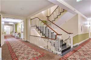 Staircase featuring crown molding and carpet floors