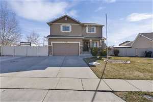 View of front of home featuring a garage, beautifully landscaped yard with large RV Pad and gate to access backyard