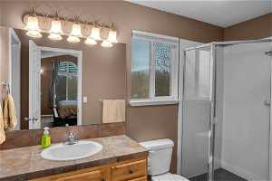 Bathroom featuring a healthy amount of sunlight, toilet, vanity with extensive cabinet space, and walk in shower