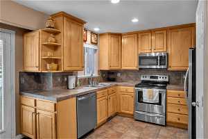 Kitchen featuring light tile flooring, stainless steel appliances, tasteful backsplash, and sink