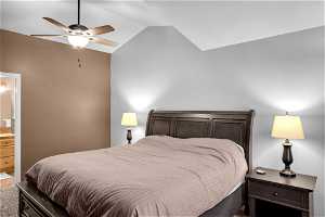 Carpeted bedroom featuring vaulted ceiling, connected bathroom, and ceiling fan
