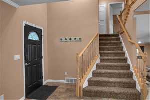 Tiled entryway featuring crown molding