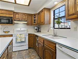 Kitchen with sink, white appliances, and dark tile flooring
