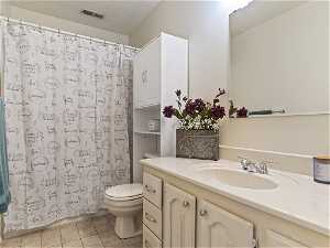 Bathroom featuring vanity, tile flooring, a textured ceiling, and toilet