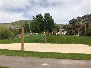 View of home's community featuring a mountain view, volleyball court, and a lawn