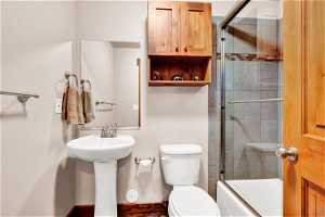 Bathroom featuring combined bath / shower with glass door and toilet