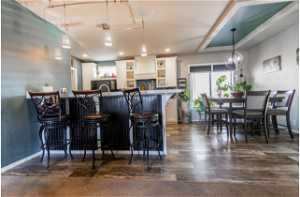 Kitchen featuring dark hardwood / wood-style floors, pendant lighting, a kitchen breakfast bar, and white cabinets