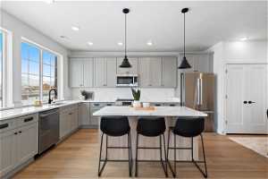 Kitchen featuring light stone countertops, light wood-type flooring, stainless steel appliances, and a center island