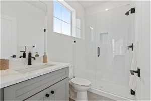 Bathroom with a shower with shower door, tile floors, large vanity, and toilet