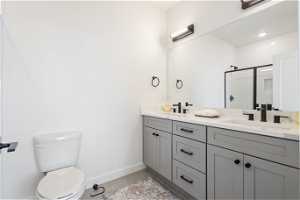Bathroom with toilet, dual sinks, vanity with extensive cabinet space, and tile flooring