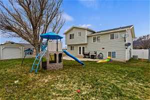 Rear view of property featuring central AC unit, a playground, a patio, and a yard