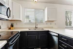 Kitchen with appliances with stainless steel finishes, white cabinets, and sink