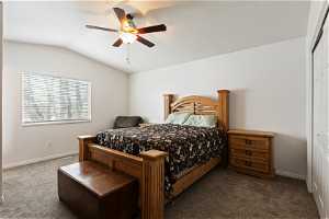 Carpeted bedroom with a closet, lofted ceiling, and ceiling fan