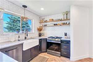 Kitchen featuring backsplash, stainless steel appliances, light parquet floors, sink, and hanging light fixtures