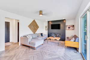 Living room featuring a large fireplace, ceiling fan, and light parquet flooring