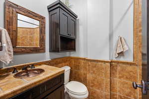 Bathroom featuring large vanity, tile walls, and toilet