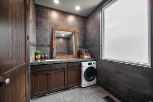 Bathroom featuring tile floors, vanity, washer / clothes dryer, and tile walls