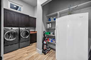 Laundry area featuring cabinets, light hardwood / wood-style flooring, and separate washer and dryer