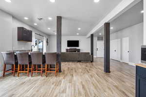 Kitchen with dark brown cabinets, light hardwood / wood-style flooring, and a kitchen bar