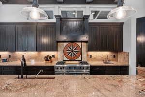 Kitchen featuring double oven range, pendant lighting, tasteful backsplash, and sink