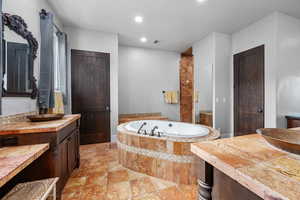 Bathroom with tiled tub, vanity with extensive cabinet space, and tile floors