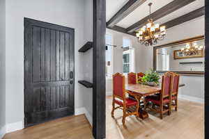 Dining space with an inviting chandelier, light hardwood / wood-style flooring, and beam ceiling