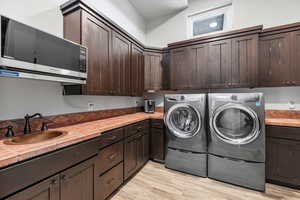 Laundry room with sink, light hardwood / wood-style floors, and separate washer and dryer