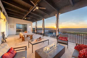 Patio terrace at dusk with a water view, a fire pit, and ceiling fan