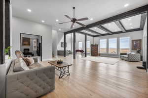 Living room with light wood-type flooring, beamed ceiling, and ceiling fan