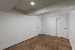 Basement featuring dark colored carpet and a textured ceiling