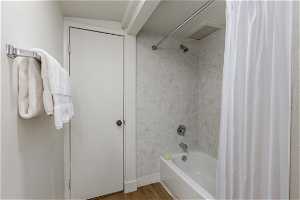 Bathroom with wood-type flooring and shower / bathtub combination with curtain