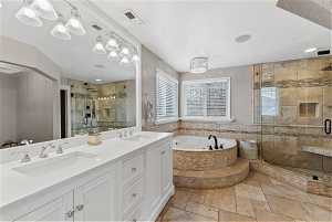 Bathroom with tile flooring, independent shower and bath, oversized vanity, and dual sinks